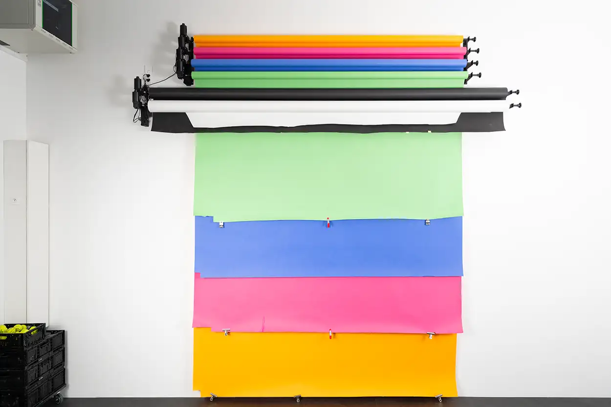 Système de fonds motorisé avec rouleaux de papier colorés — orange, rose, bleu, vert, noir, blanc — déployés sur le plateau de Greystone Studio à Villeurbanne Lyon