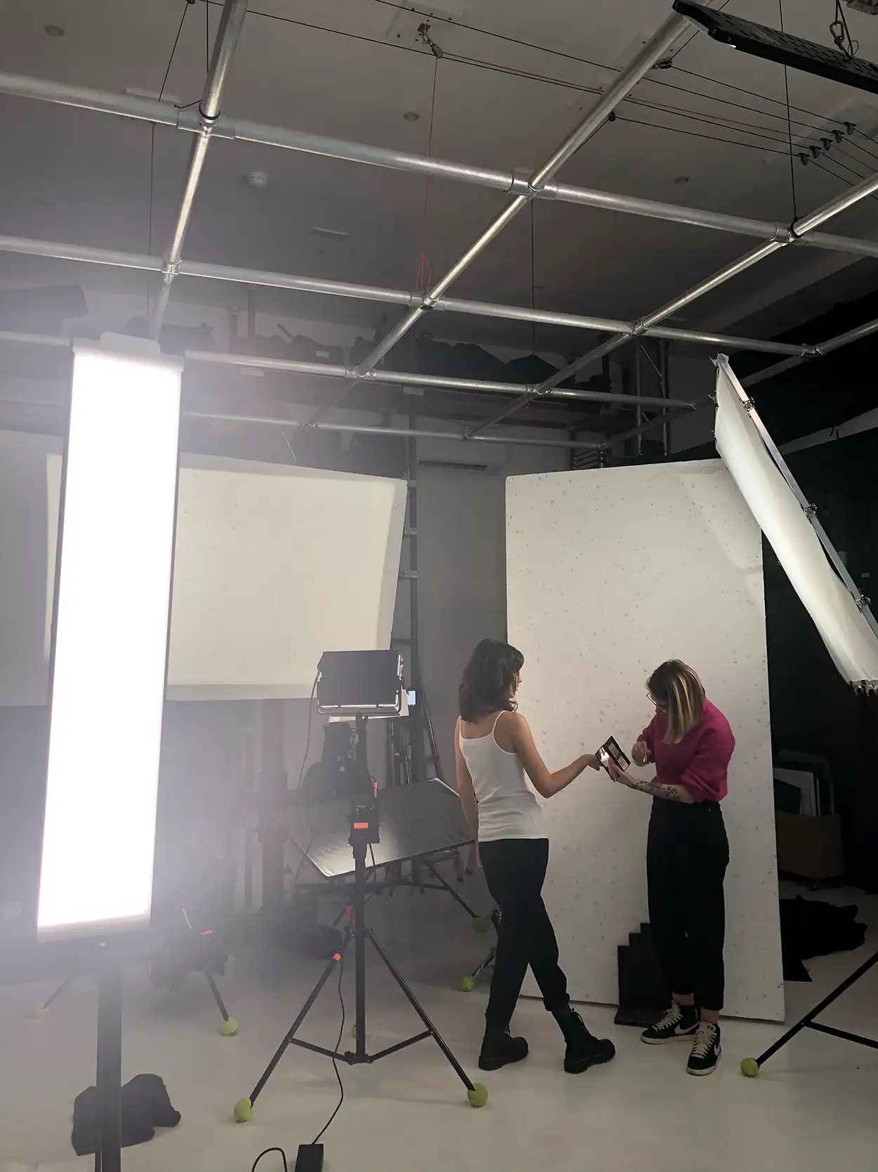 Deux personnes consultant un moniteur sur le plateau de Greystone Studio, panneau LED tubulaire et fond blanc, préparation shooting mode lookbook Villeurbanne Lyon