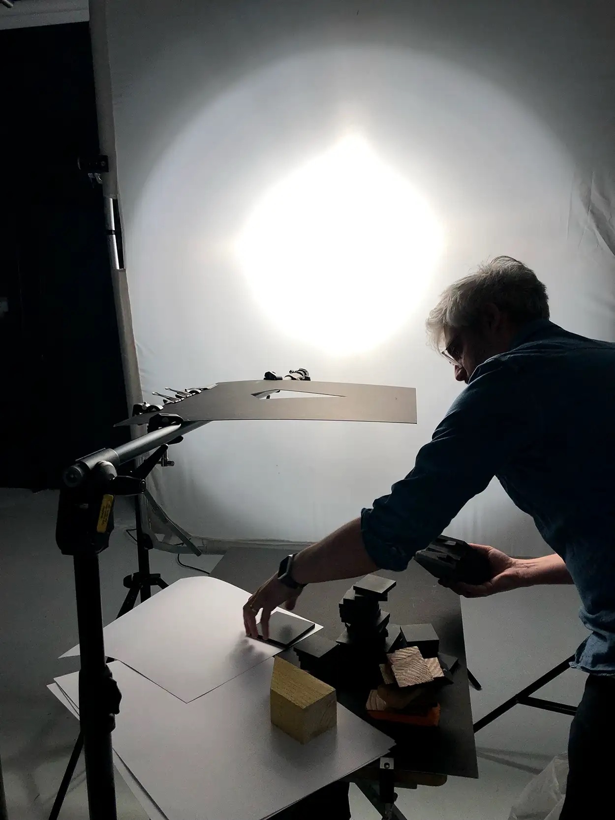 Photographe positionnant des matières et cubes sur plateau packshot éclairé par grand octobox, Greystone Studio Lyon