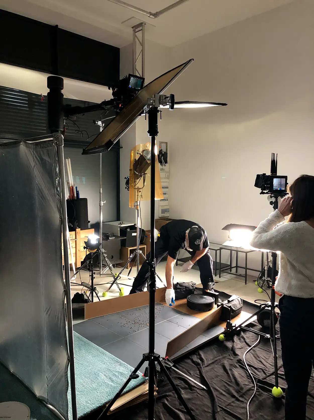 Équipe préparant un plateau packshot high-tech avec flash Fresnel et caméra sur fond sombre, Greystone Studio Lyon
