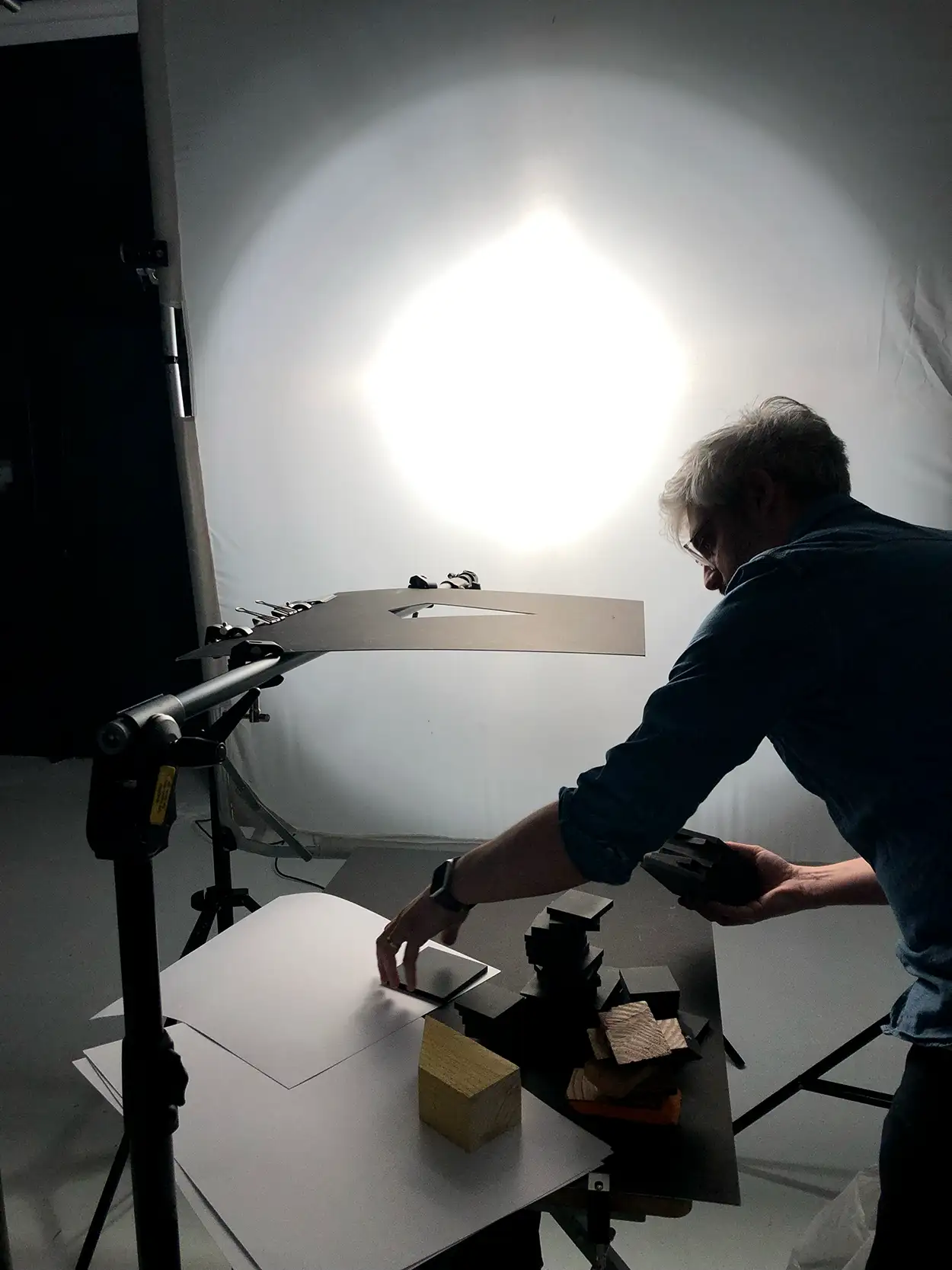 Photographe positionnant des matières et cubes sur plateau packshot éclairé par grand octobox, Greystone Studio Lyon